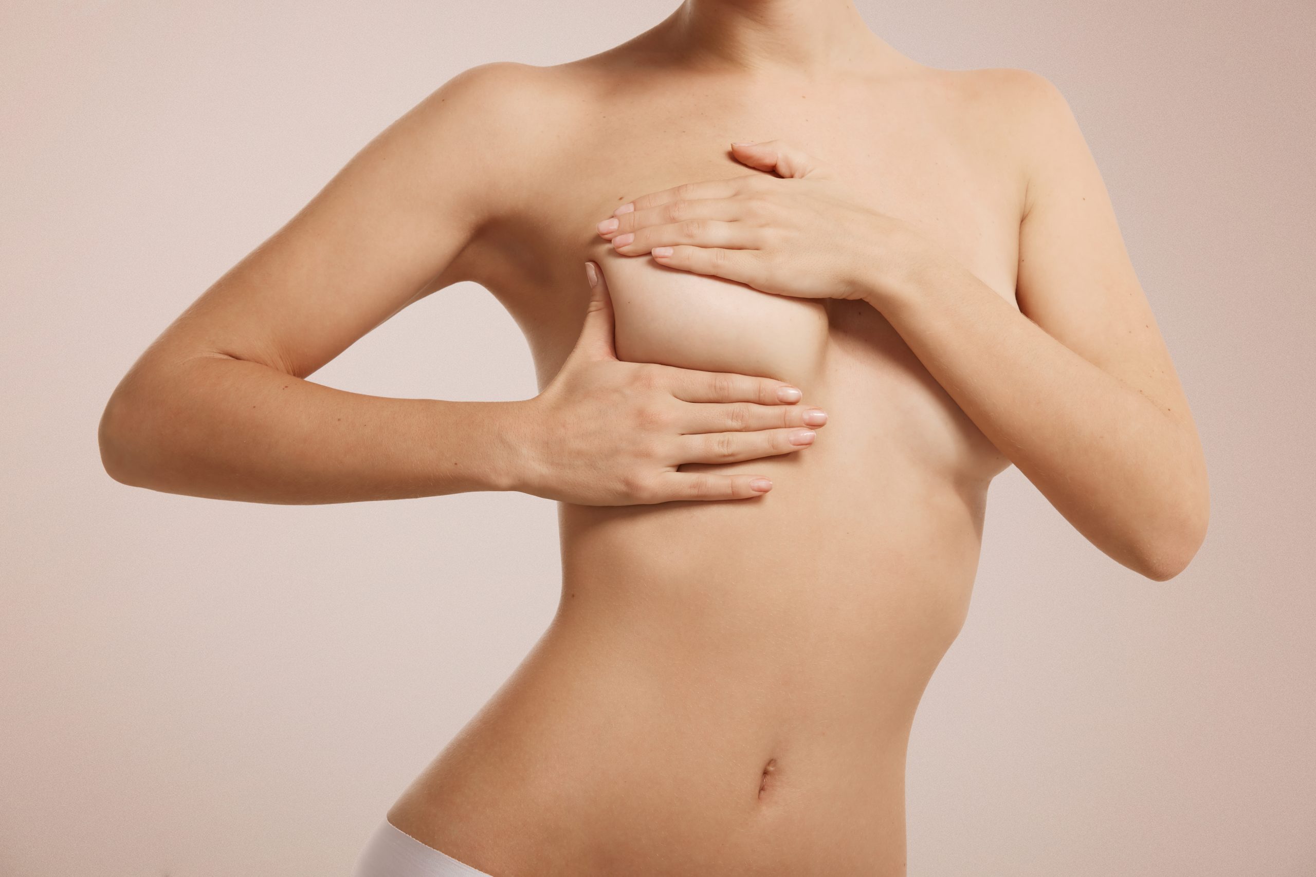 Breast cancer self check, healthy lifestyle concept. Young pretty woman examining her breast for lumps or signs of breast cancer